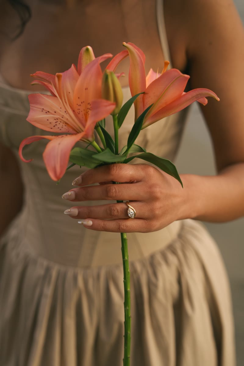 Naomi holding a lily, showing her engagement ring