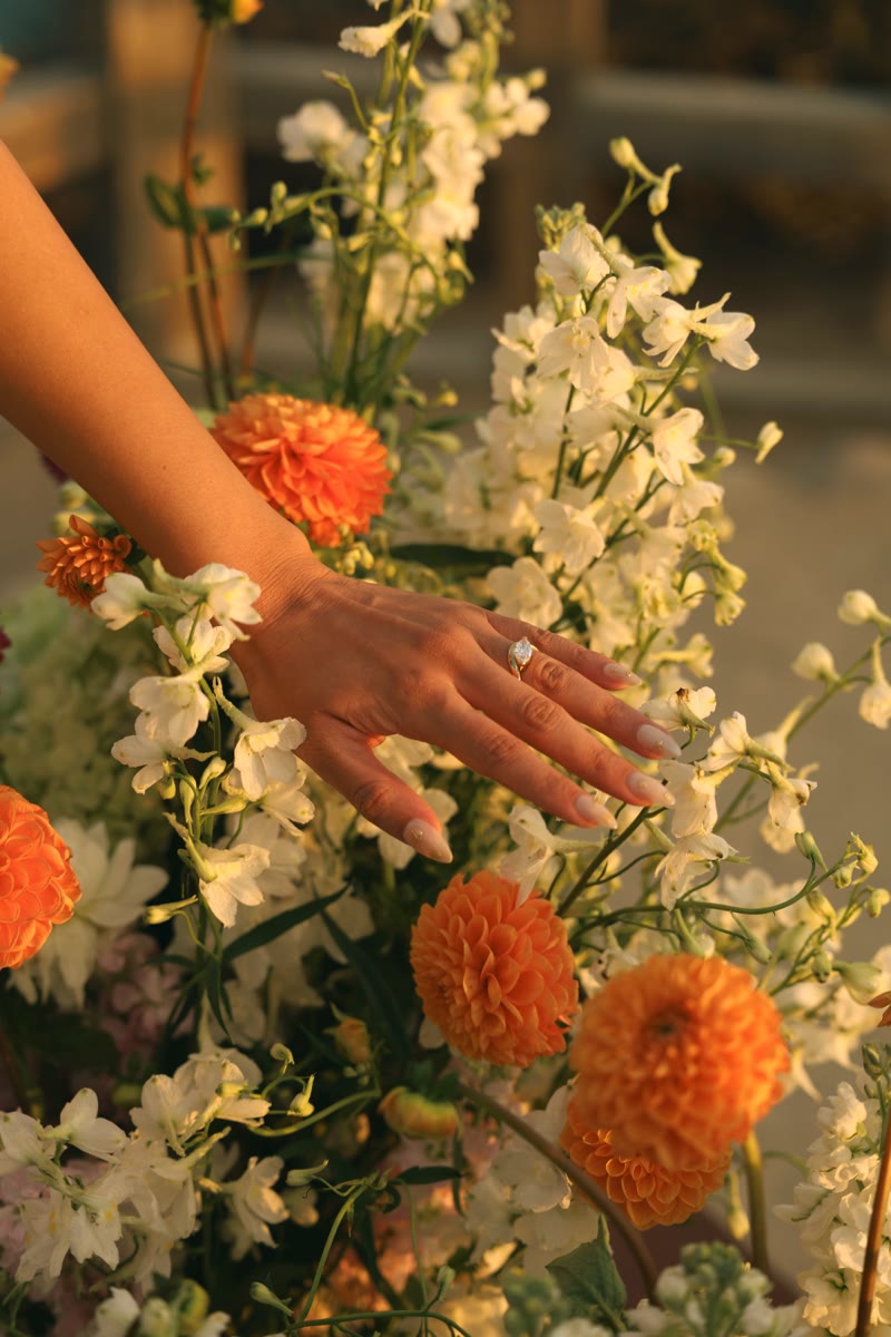 Naomi's hand brushing the proposal flowers